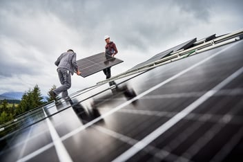 Solar panels being installed on a rooftop, reflecting the cloudy sky. They harness sunlight to generate clean, renewable energy, reducing reliance on fossil fuels and lowering electricity costs.