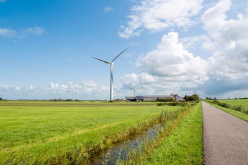 Countryside field with a wind turbine in the background, illustrating renewable energy as part of decarbonisation efforts